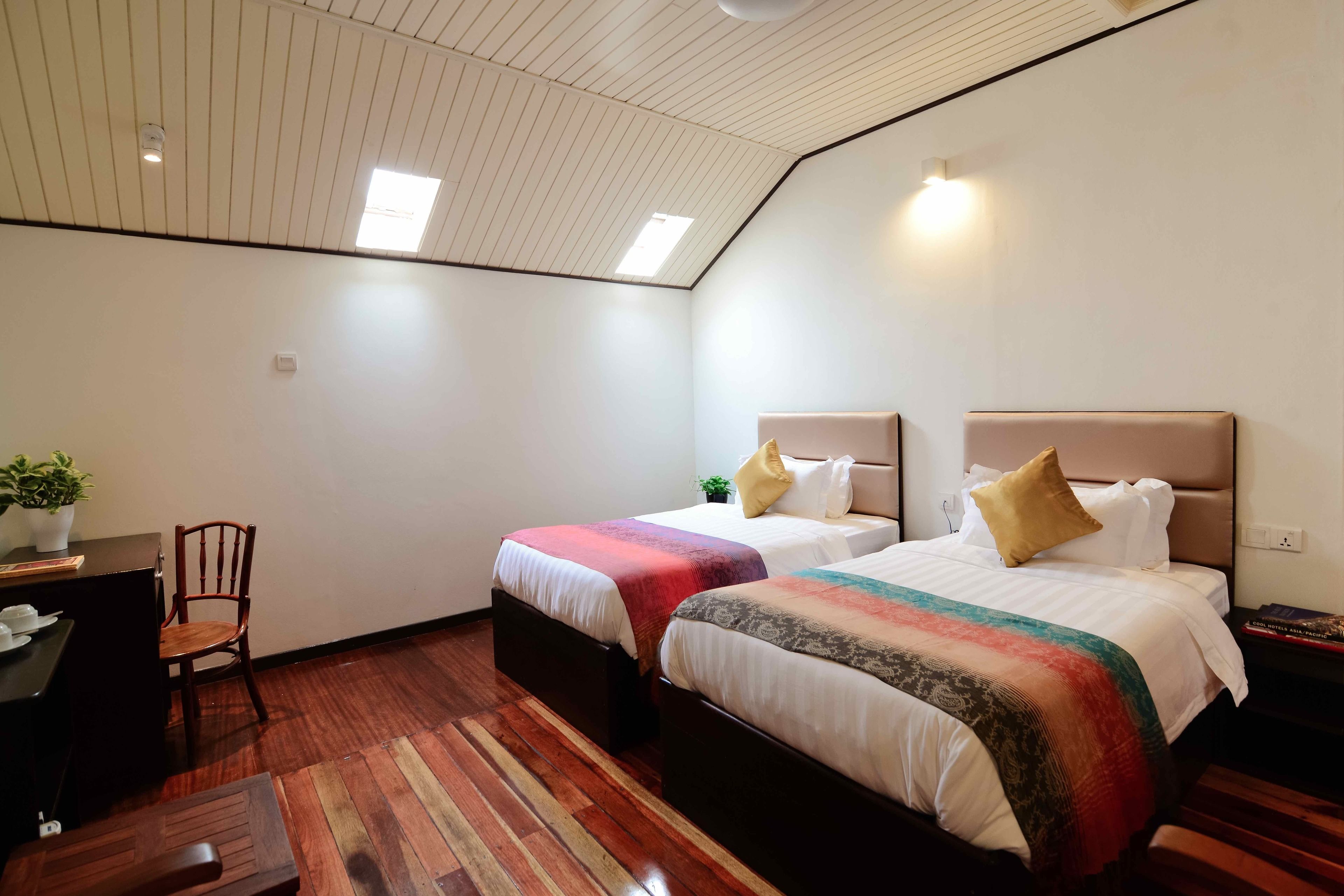 Quarto com duas camas, uma escrivaninha e uma cadeira.