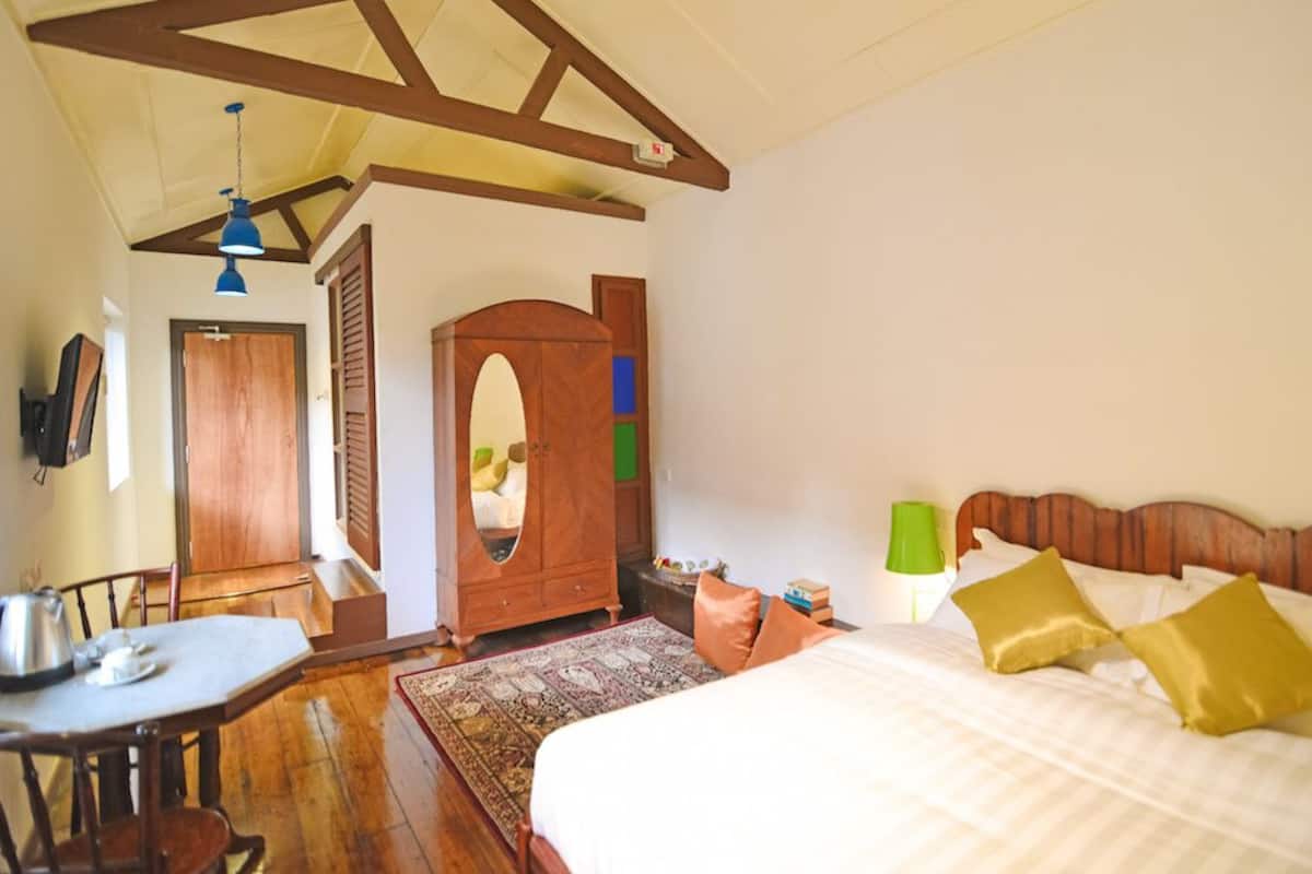 Une chambre à coucher avec un lit, une armoire en bois et une table à manger avec des chaises.