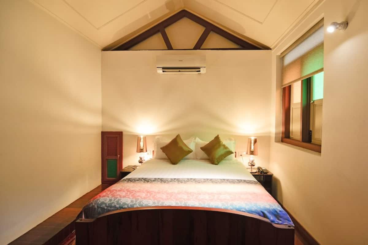 Une chambre à coucher avec un cadre de lit en bois, une grande fenêtre avec stores, un appareil de climatisation et des lampes de chevet.