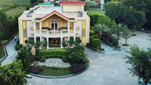 Un edificio grande de varios pisos con un patio central, rodeado de abundante vegetación y un jardín bien cuidado.