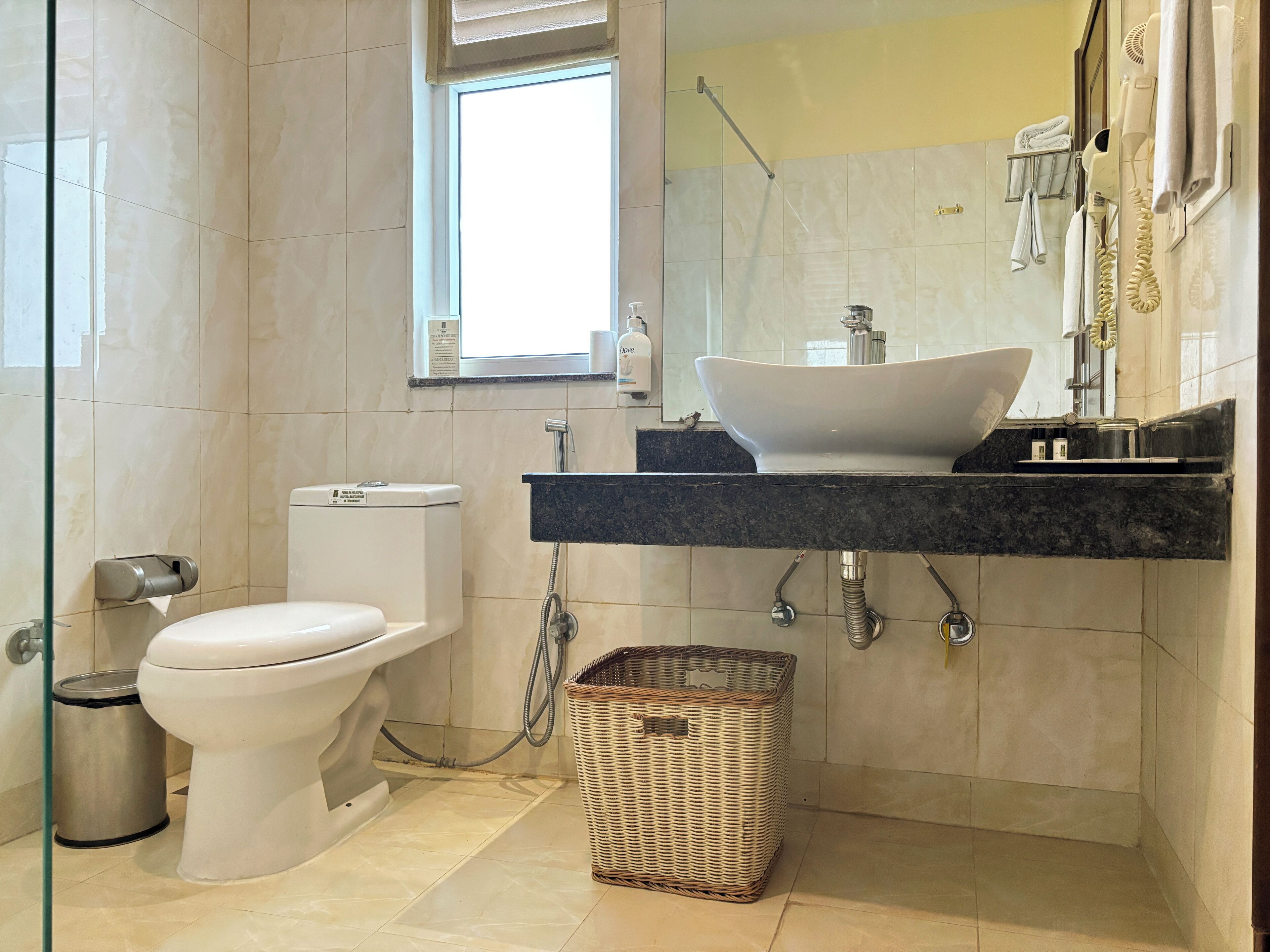 A modern bathroom with a toilet, bidet, sink, and a large mirror.