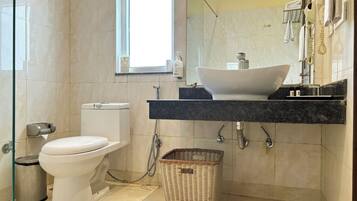 A modern bathroom with a toilet, bidet, sink, and a large mirror.