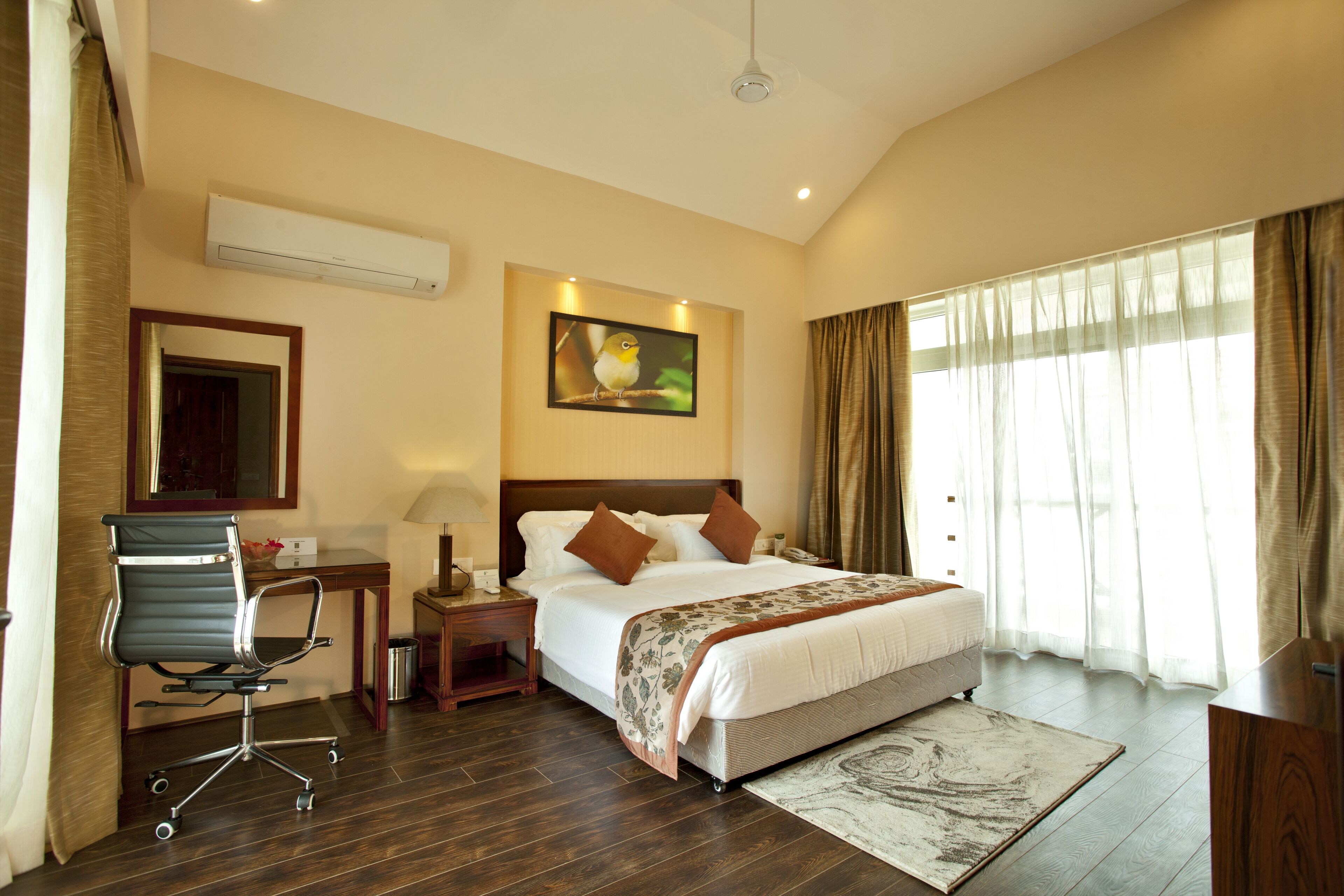 Habitación de hotel con cama, escritorio, silla y un cuadro en la pared.