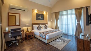 Habitación de hotel con cama, escritorio, silla, aire acondicionado y ventilador de techo.