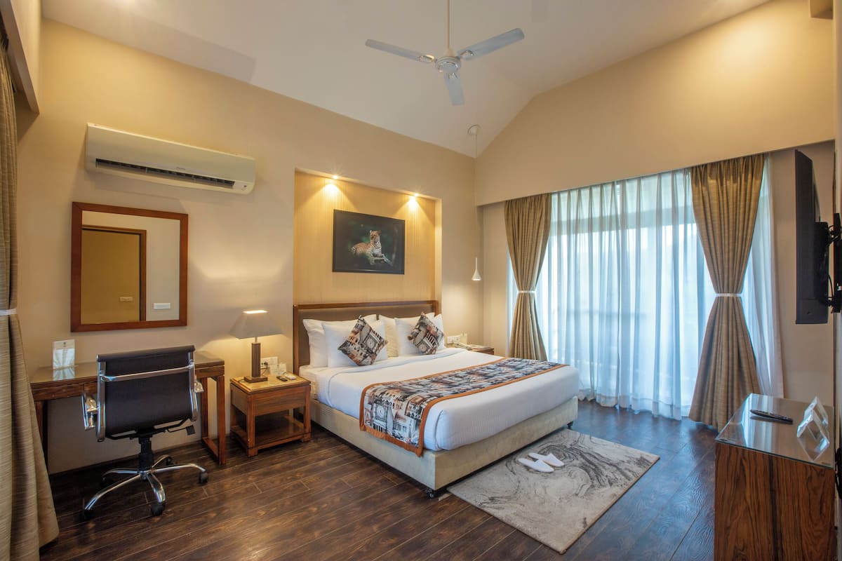 Une chambre d’hôtel équipée d’un lit, d’un bureau, d’une chaise, d’un climatiseur et d’un ventilateur de plafond.