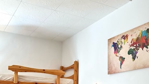 A room with a bunk bed, a single bed, a world map on the wall, and a ceiling with a floral pattern. - Albergo Varone (Riva del Garda)