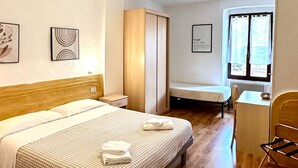 A hotel room with a bed, a desk, a chair, and a window with curtains. - Albergo Varone (Riva del Garda)