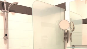 A bathroom with a glass shower enclosure, a white sink, and a stool. - Albergo Varone (Riva del Garda)
