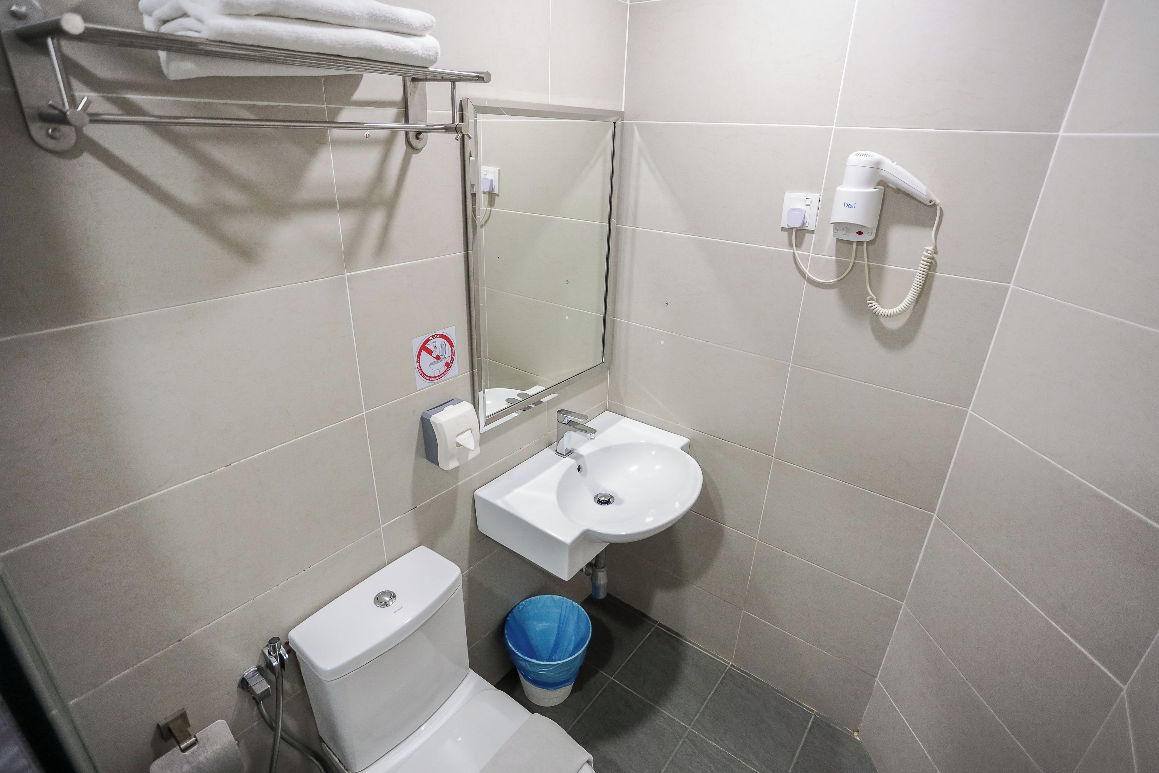 Un baño pequeño con inodoro, lavamanos y un secamanos instalado en la pared.