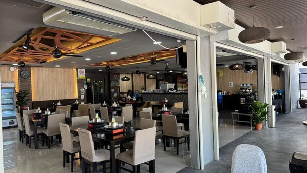 A restaurant with tables and chairs, a kitchen area, and a counter.