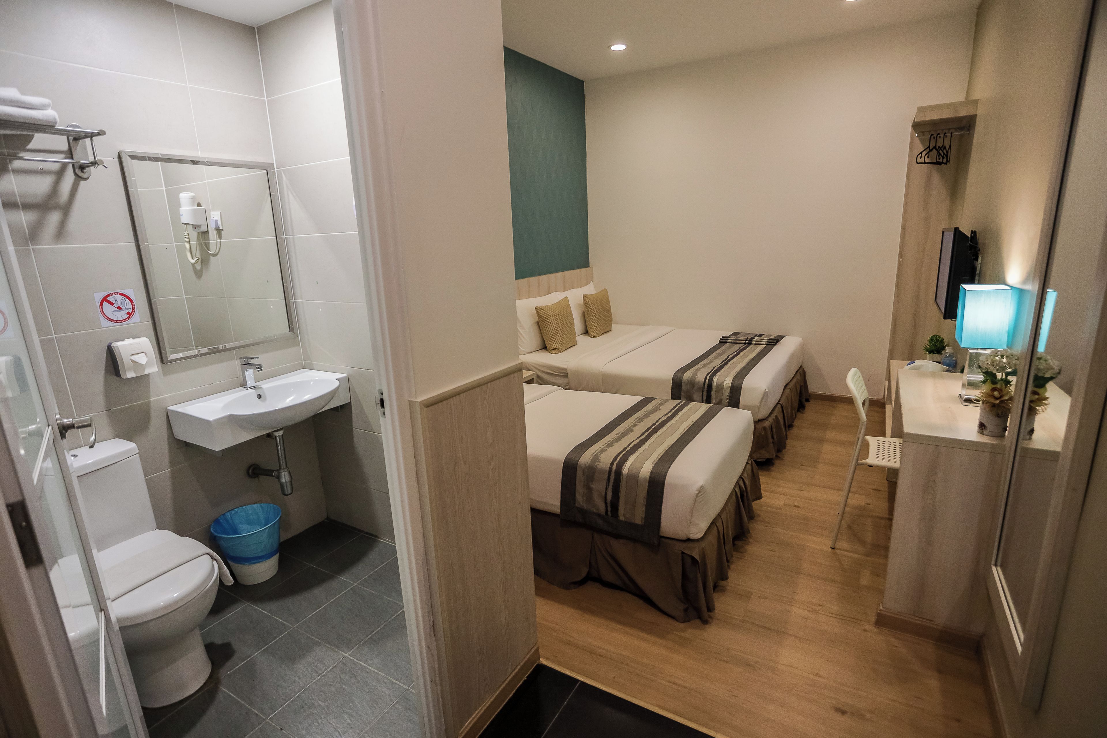 Una habitación de hotel con baño, un lavamanos, un inodoro y dos camas.