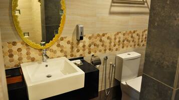 A bathroom with a white sink, a mirror with a gold frame, a towel rack, and a toilet.