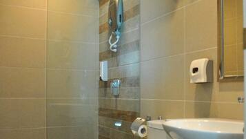 Un baño moderno con cabina de ducha de vidrio, un inodoro blanco, un lavamanos y un perchero para toallas.