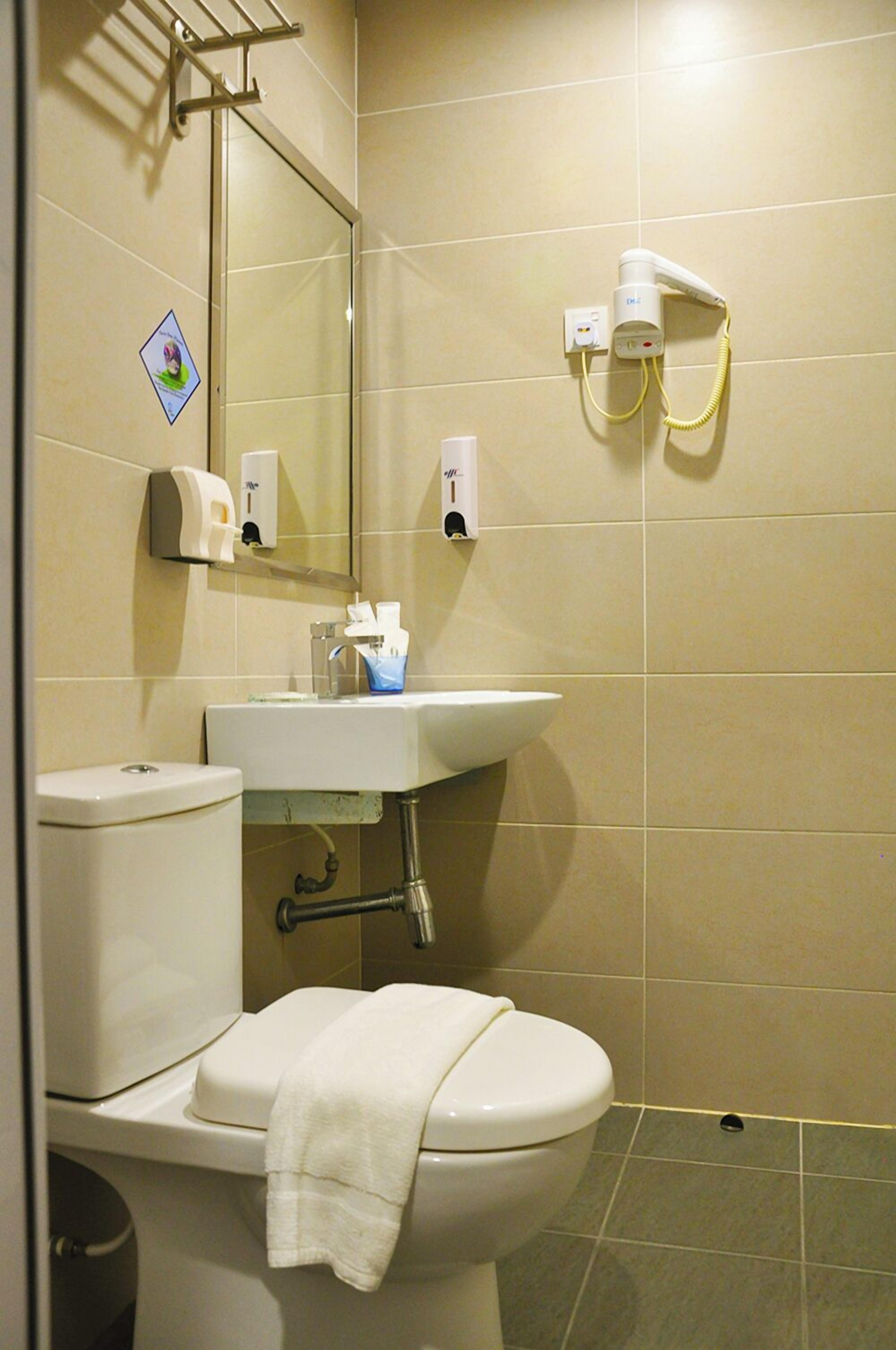Un baño con inodoro, lavamanos, espejo y toallero.