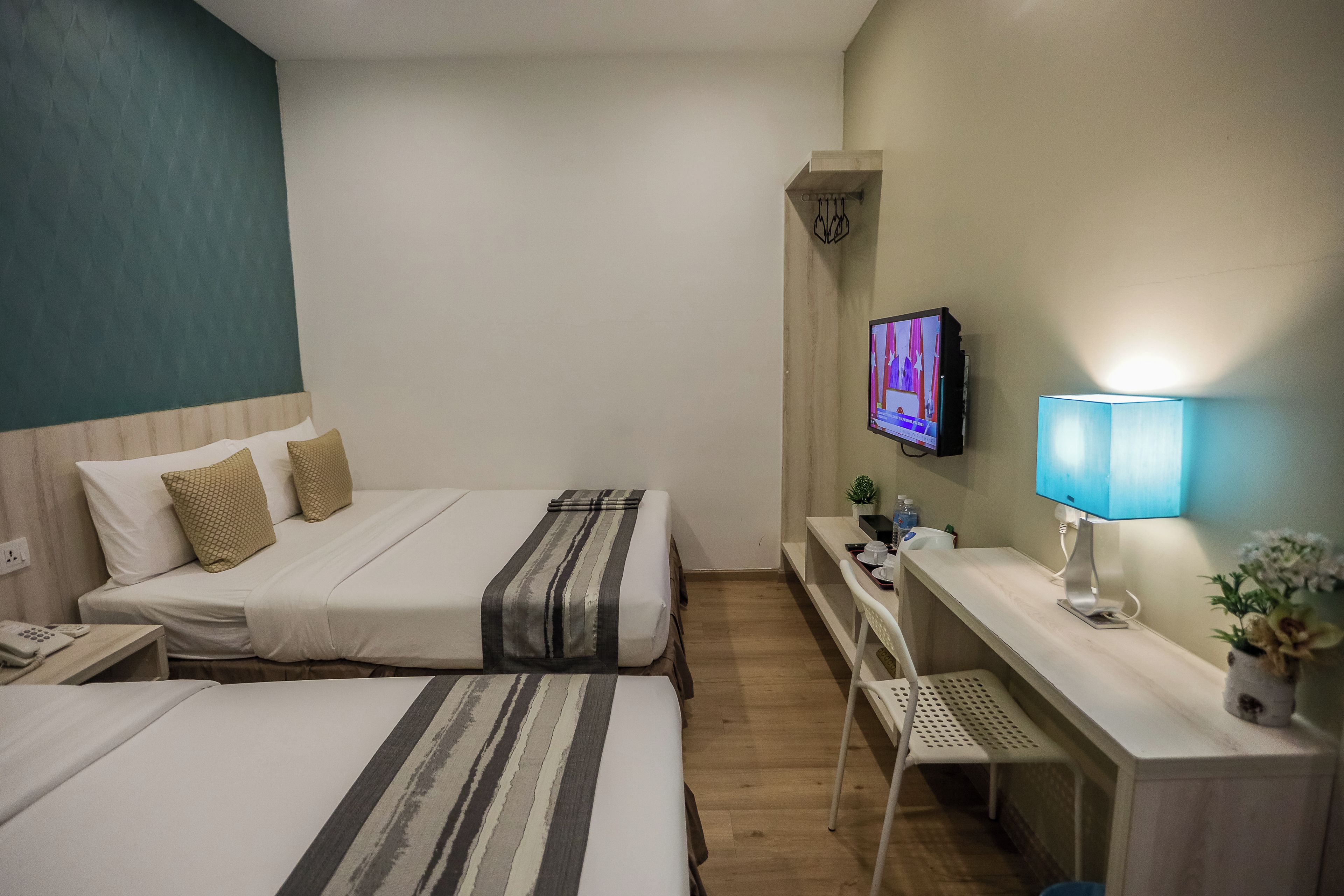 Habitación de hotel con dos camas, un escritorio, un televisor y una lámpara.