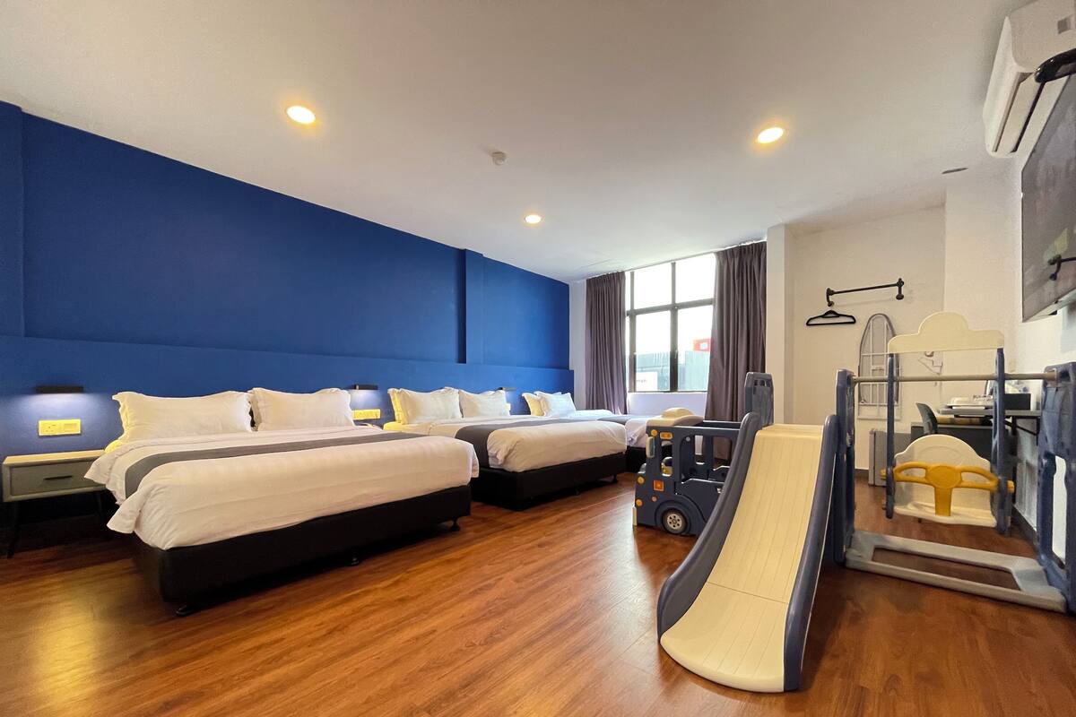Une chambre d’hôtel avec deux lits, un train jouet et une fenêtre avec des rideaux.
