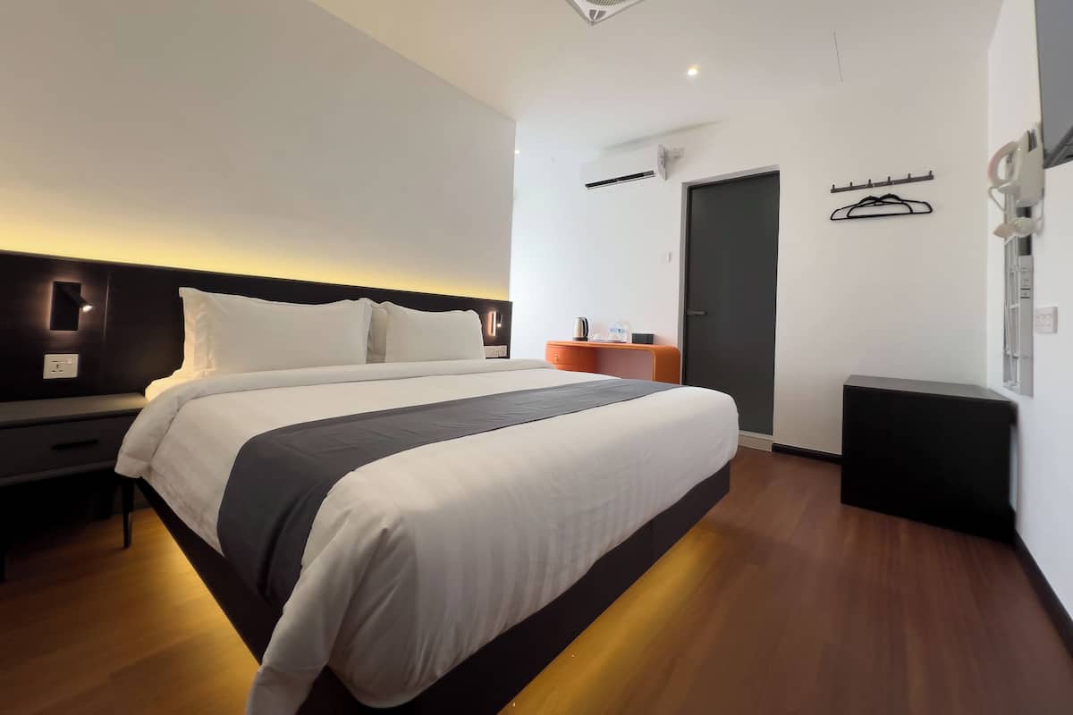 Une chambre d’hôtel moderne dotée d’un grand lit, de tables de chevet, d’une armoire, d’un téléviseur à écran plat et d’un ventilateur de plafond.