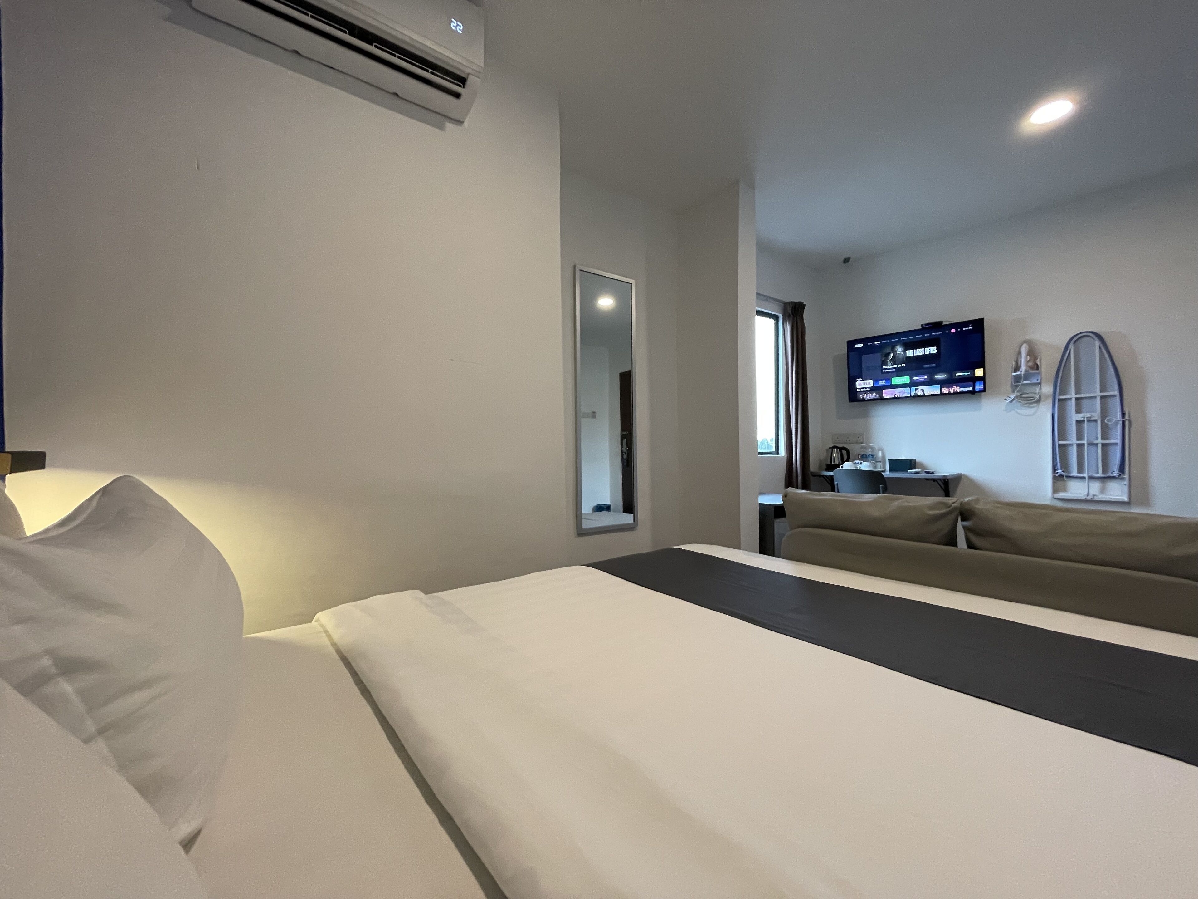 A hotel room with a bed, a desk, a chair, a TV, and a window.
