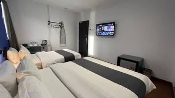 A hotel room with two beds, a TV, a desk with a chair, and a wardrobe.