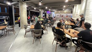 Restaurante com mesas internas, balcão para pedidos e uma televisão visível.