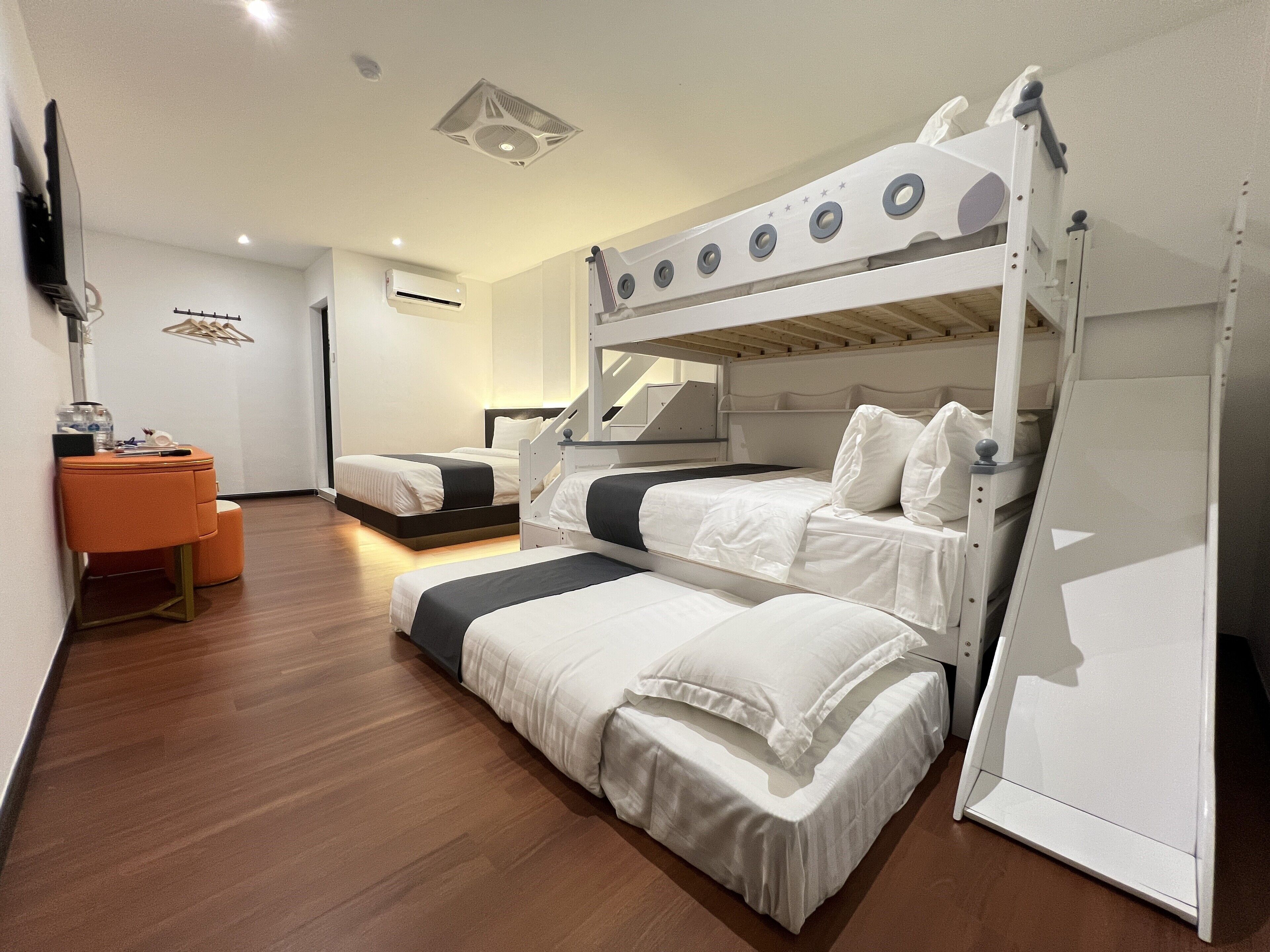 A modern hotel room with bunk beds, a desk, and a chair.