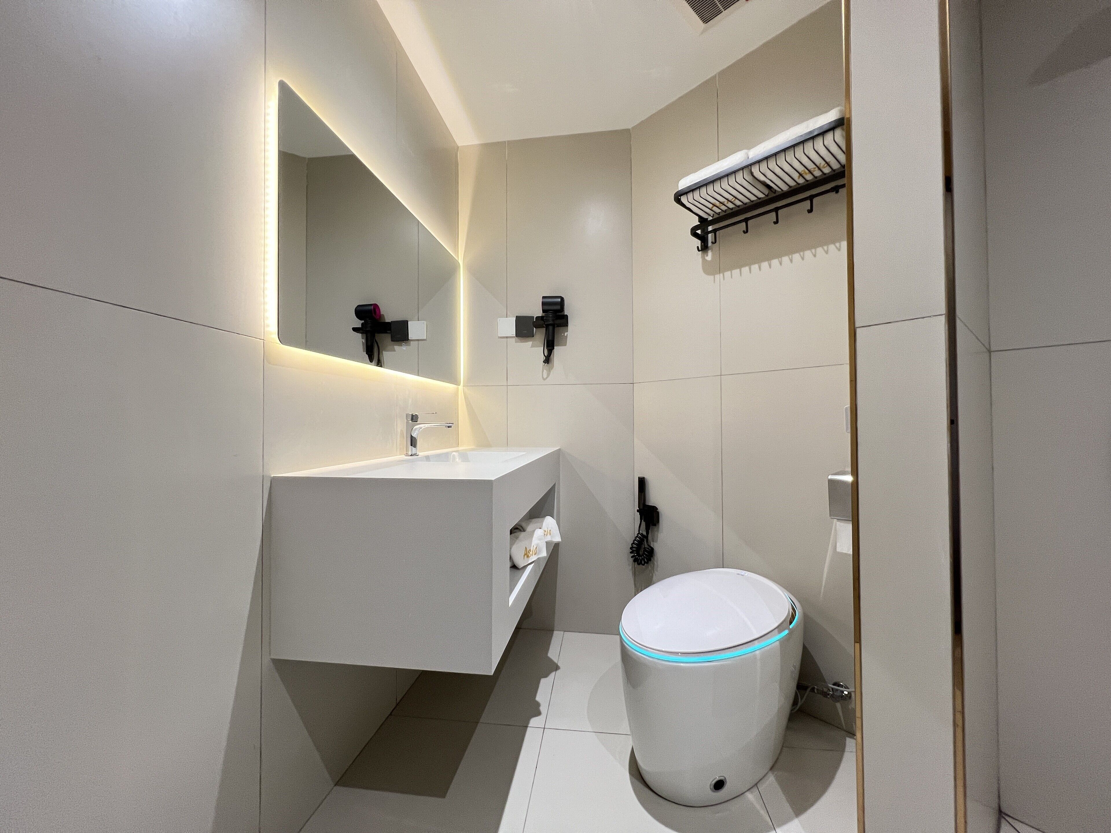 A modern bathroom with a white sink, mirror, and toilet.