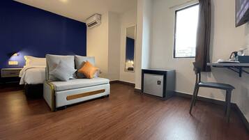 Une chambre d’hôtel moderne équipée d’un lit, d’un bureau, d’une chaise et d’un petit réfrigérateur.