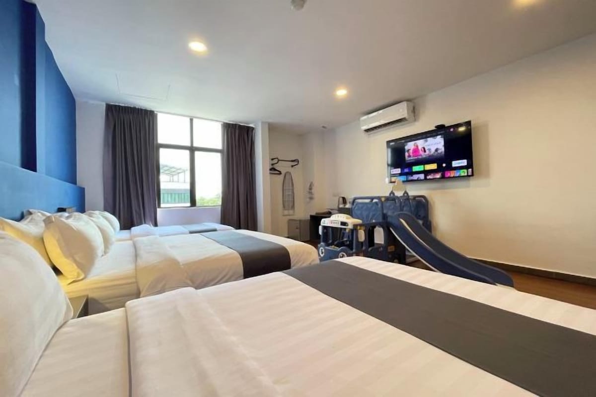 A hotel room with two beds, a TV, a desk, and a chair.