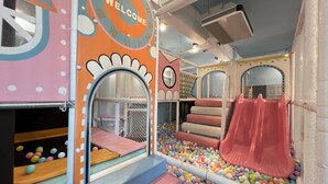 Espaço de recreação infantil com escorrega, piscina de bolinhas e estruturas de jogo fechadas.
