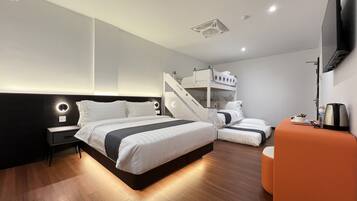 A modern hotel room with a large bed, a small seating area, and a staircase leading to an upper bunk.