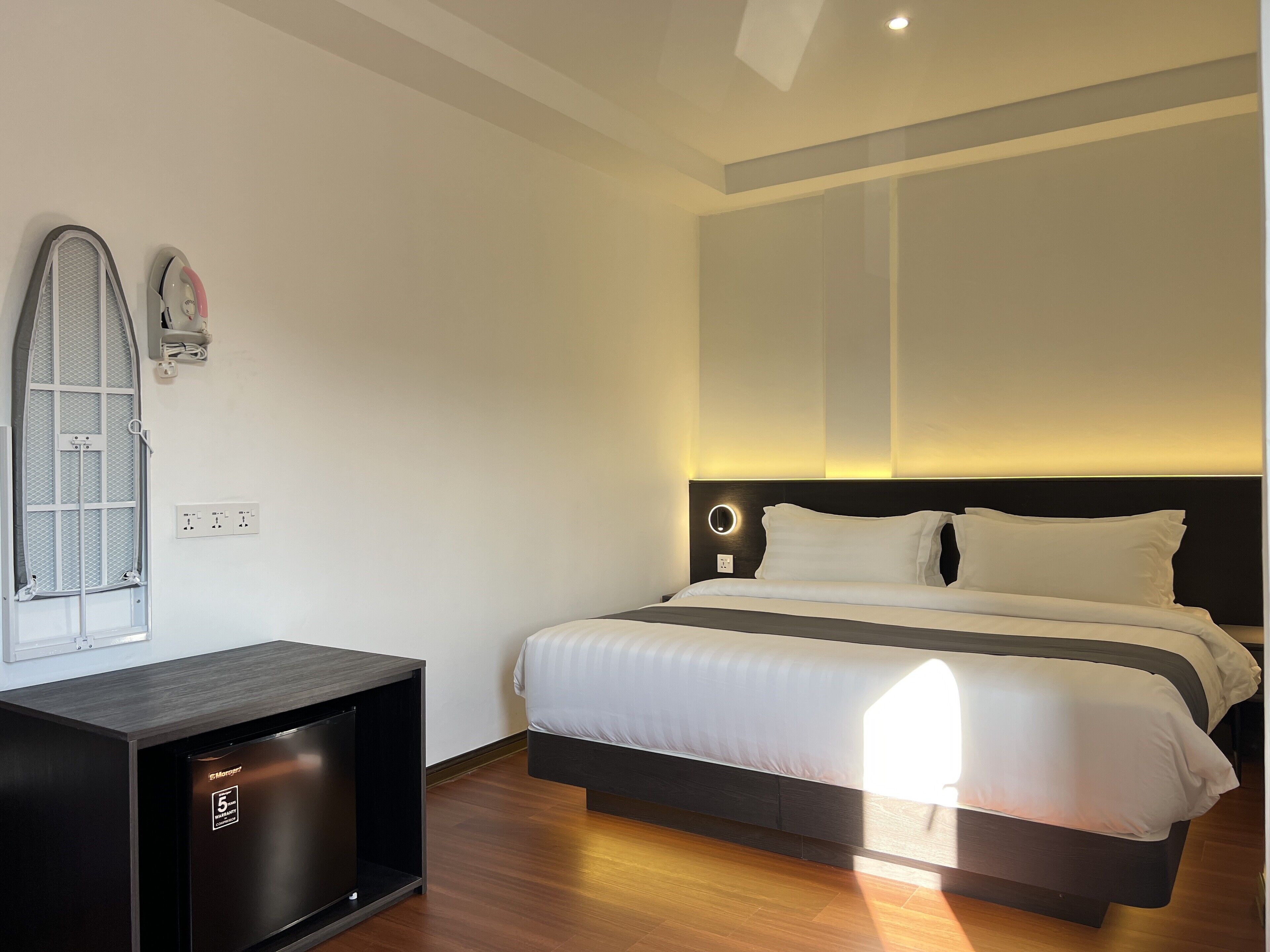 Une chambre d’hôtel moderne équipée d’un lit, d’un petit bureau et d’un téléviseur intégré.