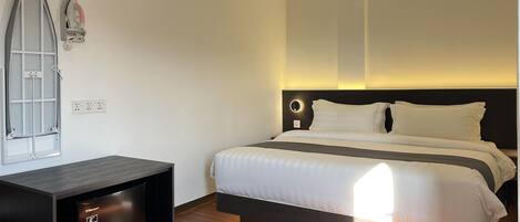 Une chambre d’hôtel moderne équipée d’un lit, d’un petit bureau et d’un téléviseur intégré.