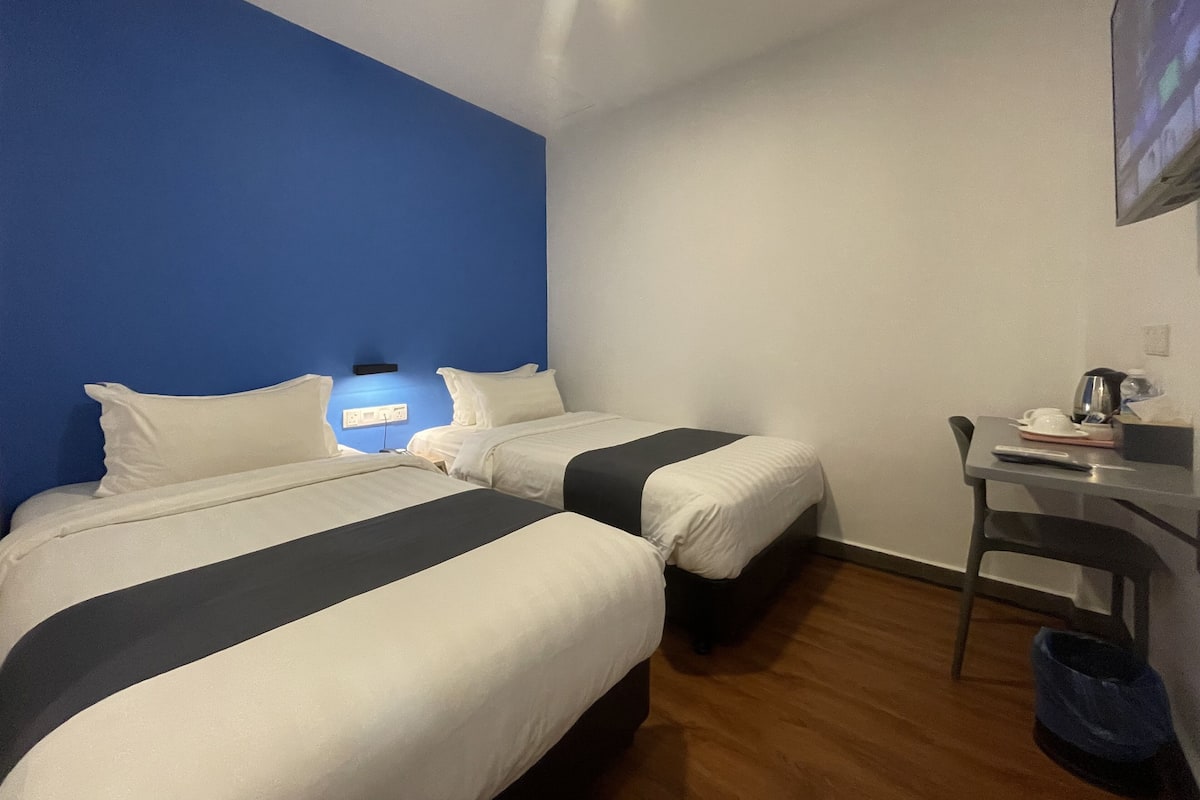 Une chambre d’hôtel avec deux lits, un bureau et une chaise.