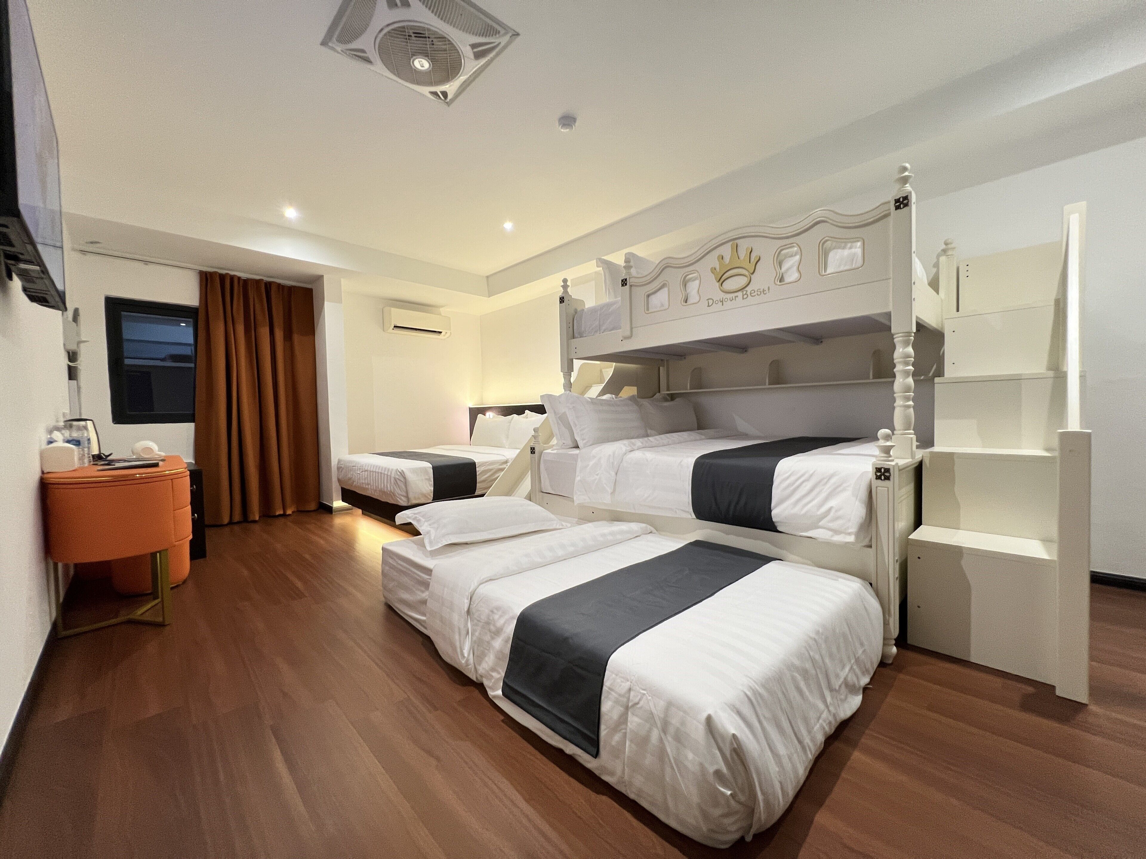 Habitación de hotel con literas, un escritorio con silla y un armario.