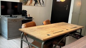 A room with a wooden table, two leather chairs, a television, a coffee machine, and a door with a handle. - Hotel BE41 (Maastricht)