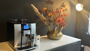 A coffee machine on a counter with a vase of flowers and a lamp. - Hotel BE41 (Maastricht)