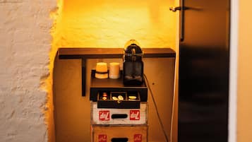 A room with a sloped ceiling, a hanging light fixture, and a speaker on a crate.