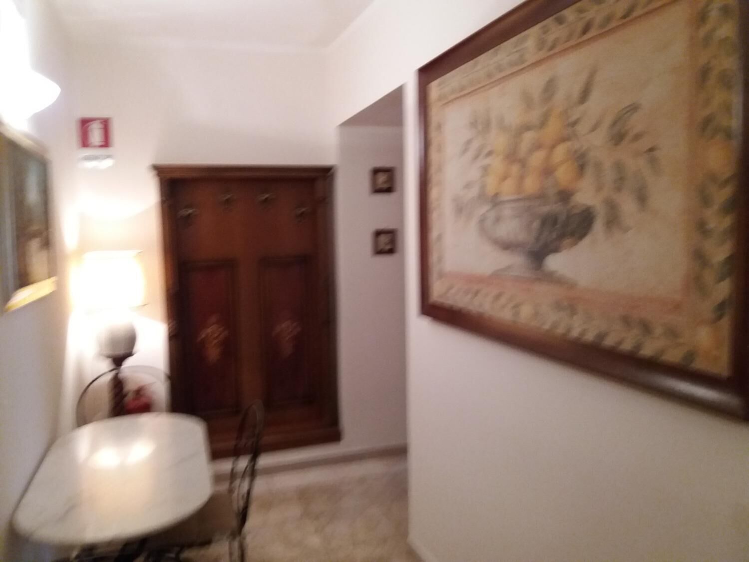 A hallway with a wooden door, a framed painting, and a white chair.