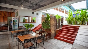 A restaurant with a wooden dining area, a staircase leading to an outdoor area, and a view of the surrounding greenery. - Joe Fisherman Inn (Pangkor Island)