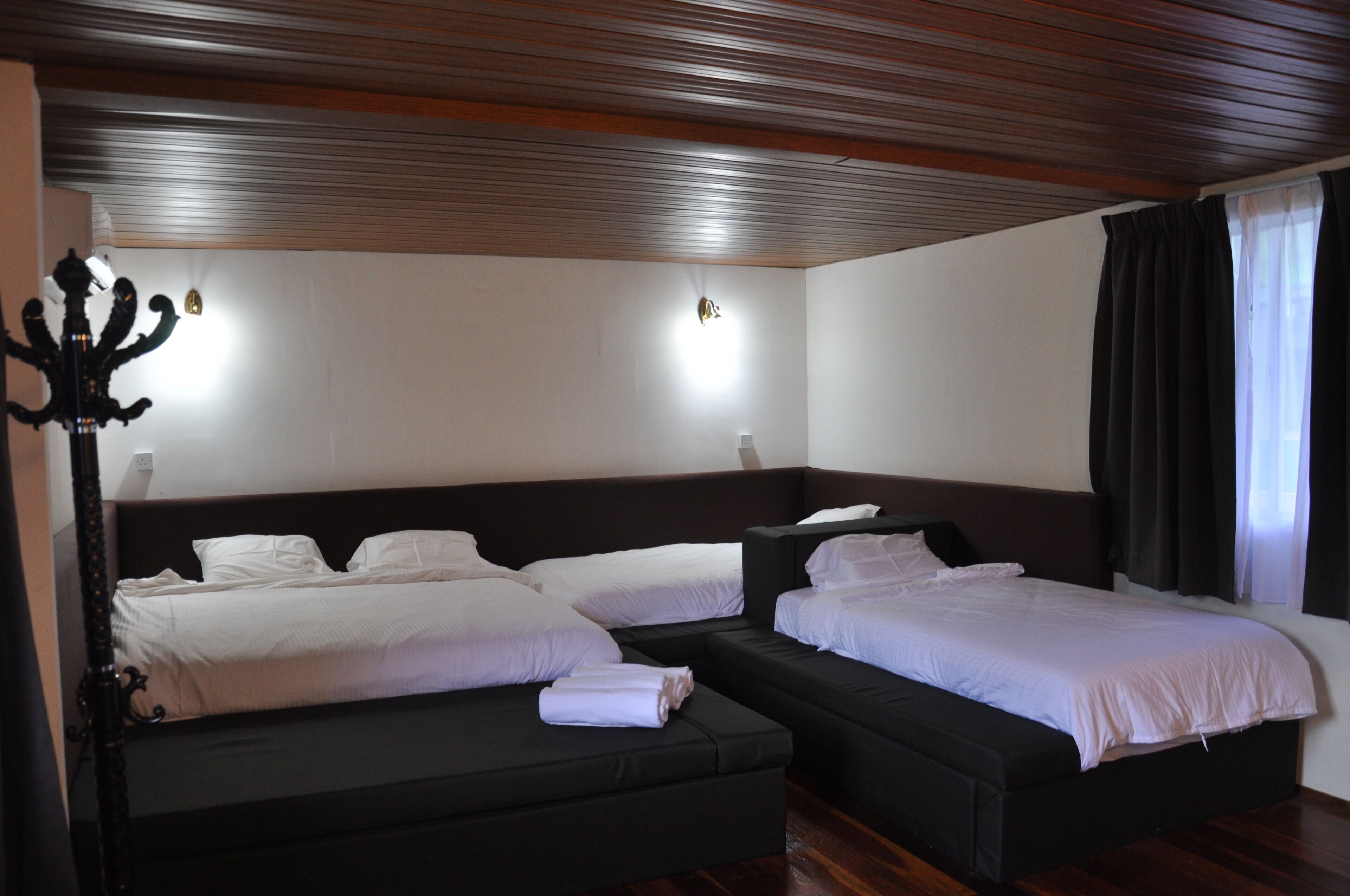 Une chambre d’hôtel avec deux lits, un plafond en bois et une table de chevet avec une lampe.