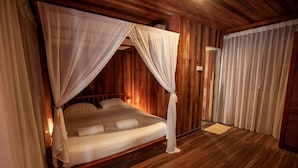 A wooden four-poster bed with white linens and a canopy, a wooden floor, and a wooden wall panel. - Joe Fisherman Inn (Pangkor Island)