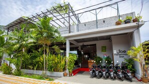 A building with a sign reading "Joe Fisherman Inn" and a row of parked motorcycles in front. - Joe Fisherman Inn (Pangkor Island)