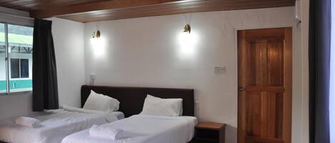 Habitación de hotel con dos camas, techo de madera, una puerta de madera y una ventana con cortinas.
