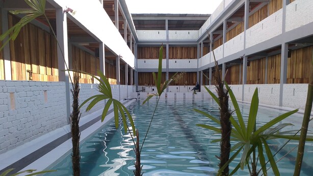 A swimming pool with a clear blue water surface, surrounded by white brick walls and wooden paneling. - Joe Fisherman Inn (Pangkor Island)