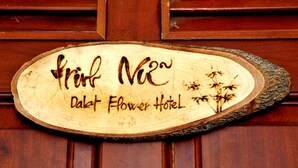 A wooden sign with the text "Print N2" and "Dalat Flower Hotel" on a wooden door.