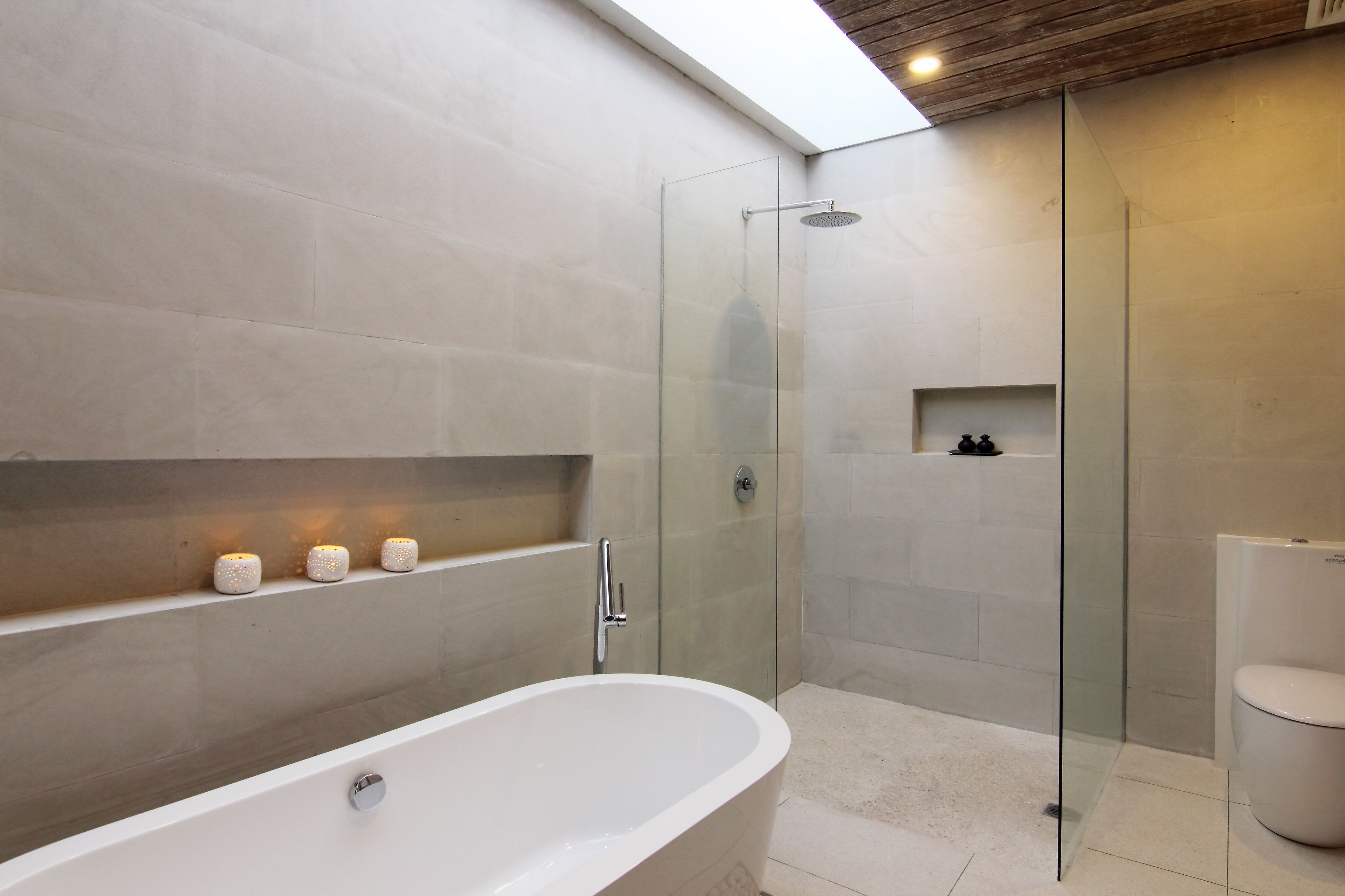 A modern bathroom with a freestanding bathtub, a glass-enclosed shower, and a toilet.