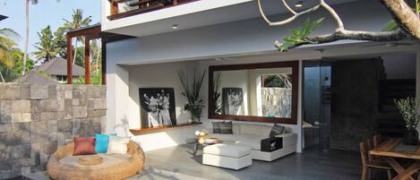 Une maison moderne dotée d’une piscine, d’un espace salon extérieur et d’une grande fenêtre donnant sur la piscine.