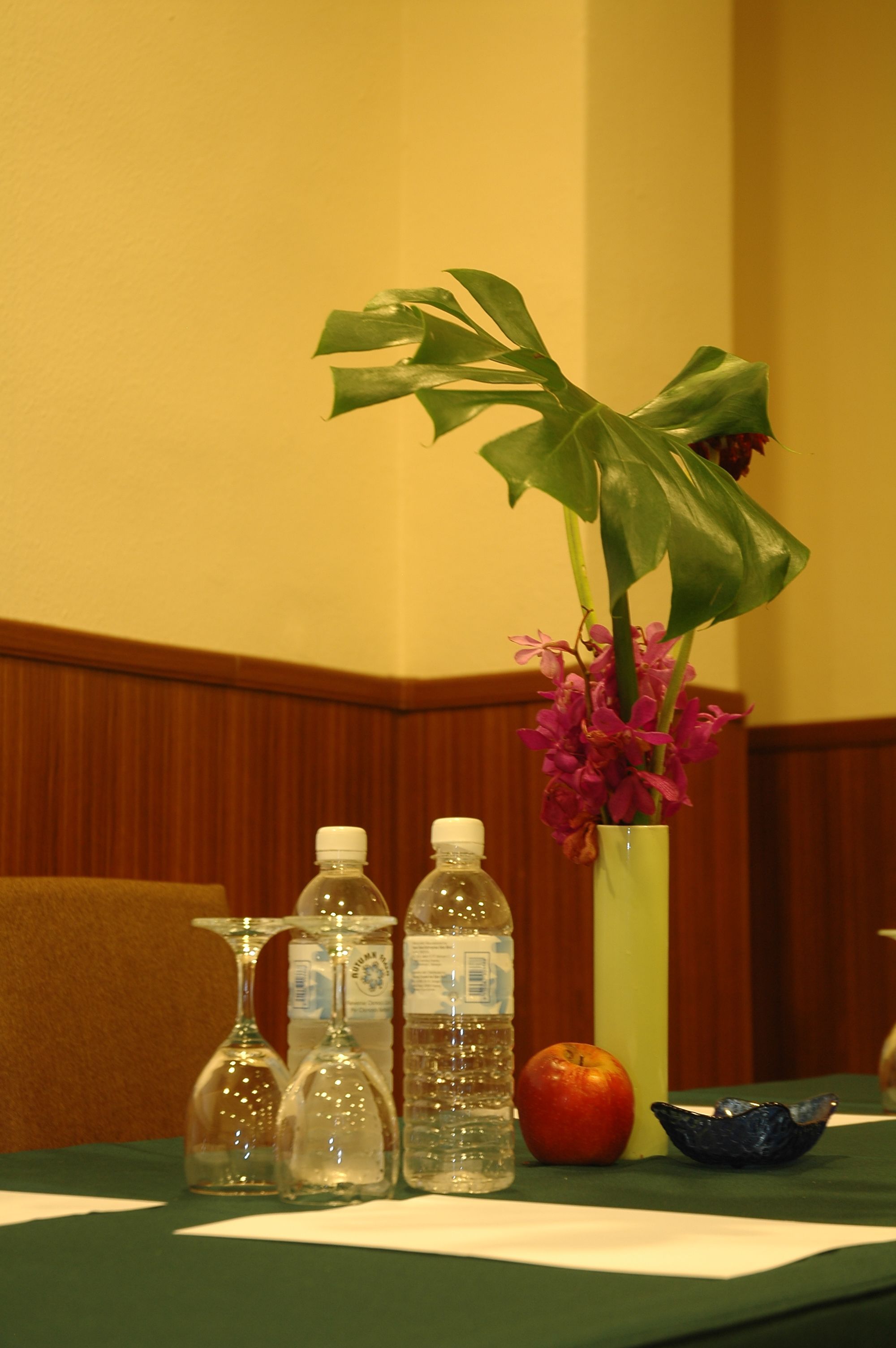 A table with a vase of flowers, a bottle, and a glass.