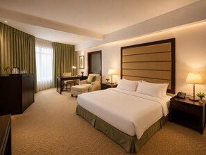 Een hotelkamer met een groot bed, een bureau, een stoel en een nachtkastje met een lamp.