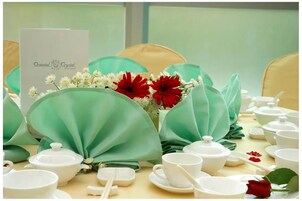 A table set with white teacups, teapots, and a menu card labeled "Oriental Crystal Hotel".